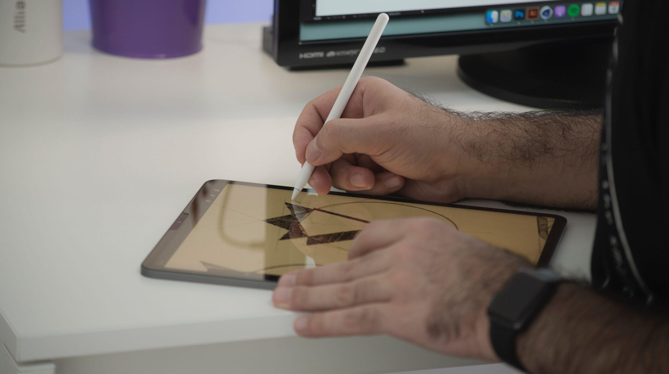 Close up of a person using a tablet to draw a logo or similar graphic.