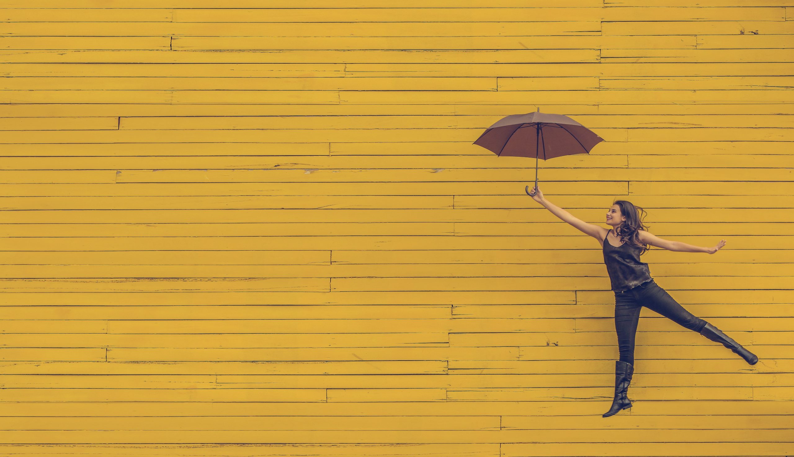 Woman jumping while holding an umbrella as part of an article about sales and marketing.