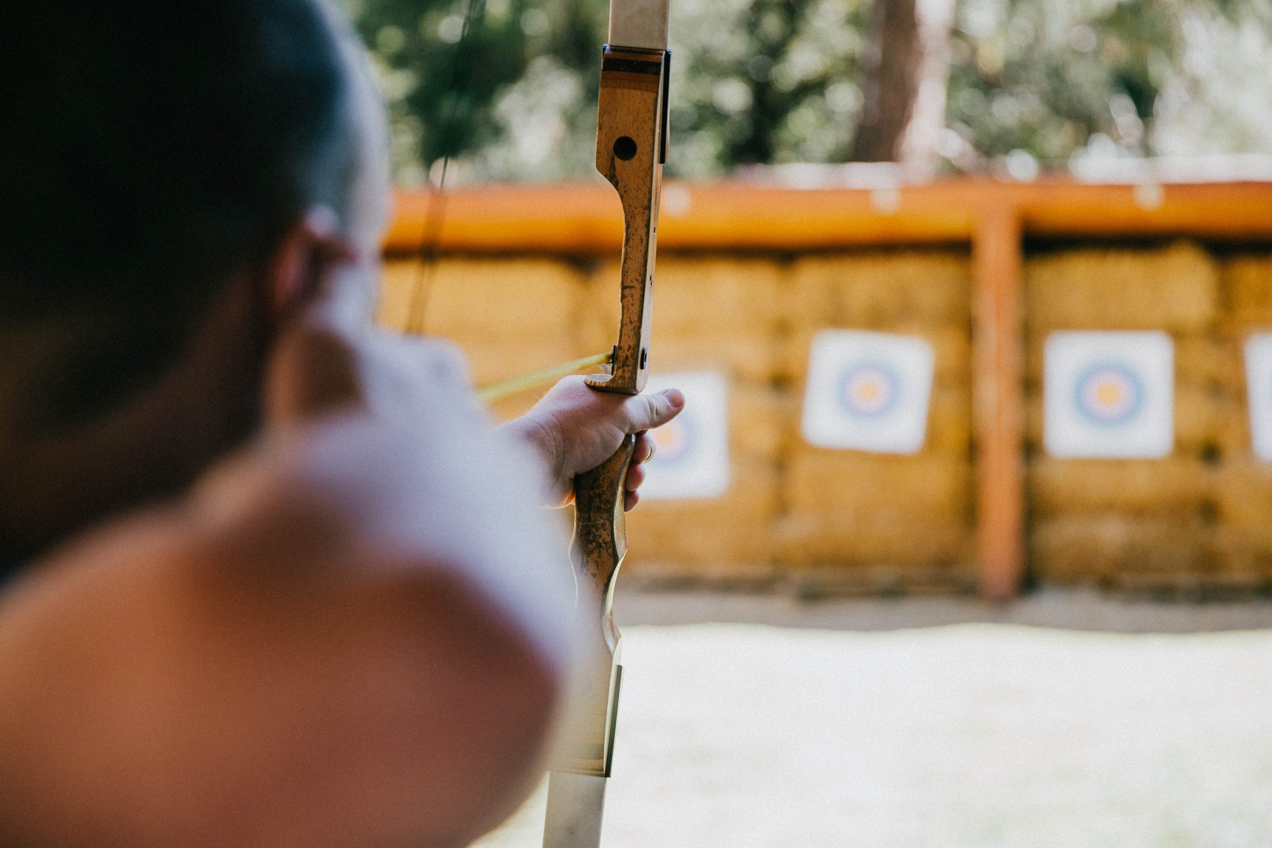 Man with bow taking aim at an archery target.
