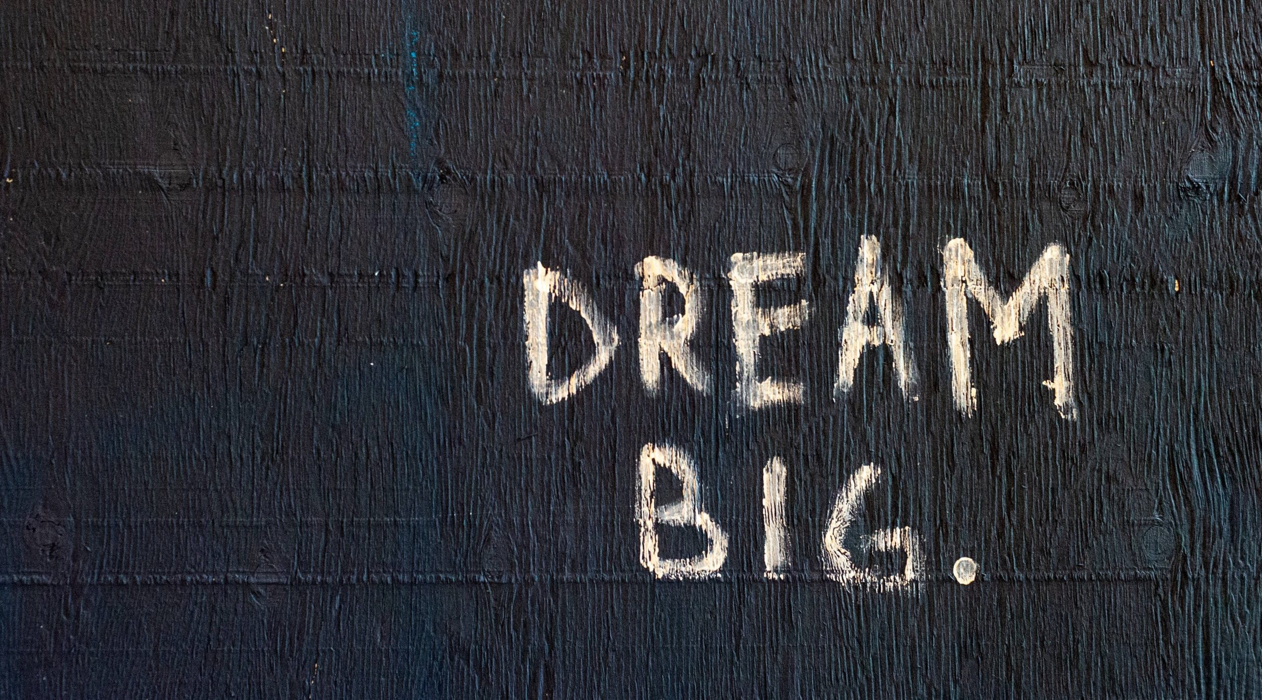 Words 'Dream Big' written on a black coloured wall.