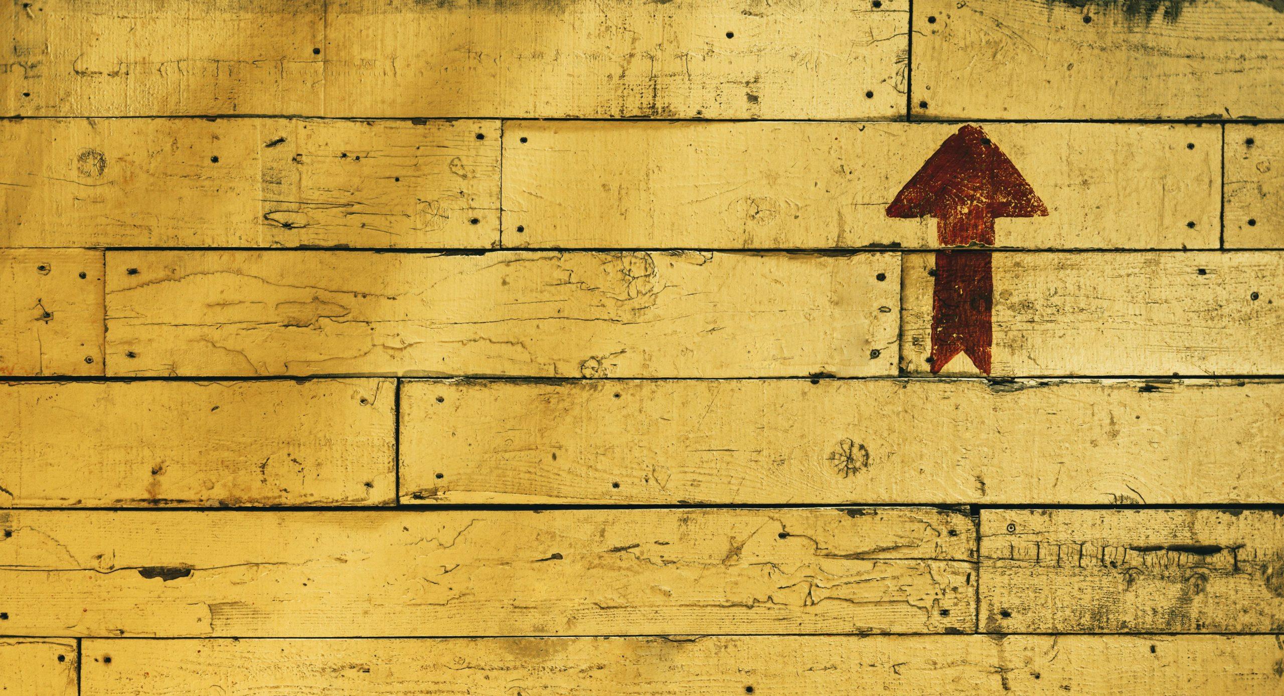 Red painted arrow against a yellow wooden wall as part of an article about value v price.