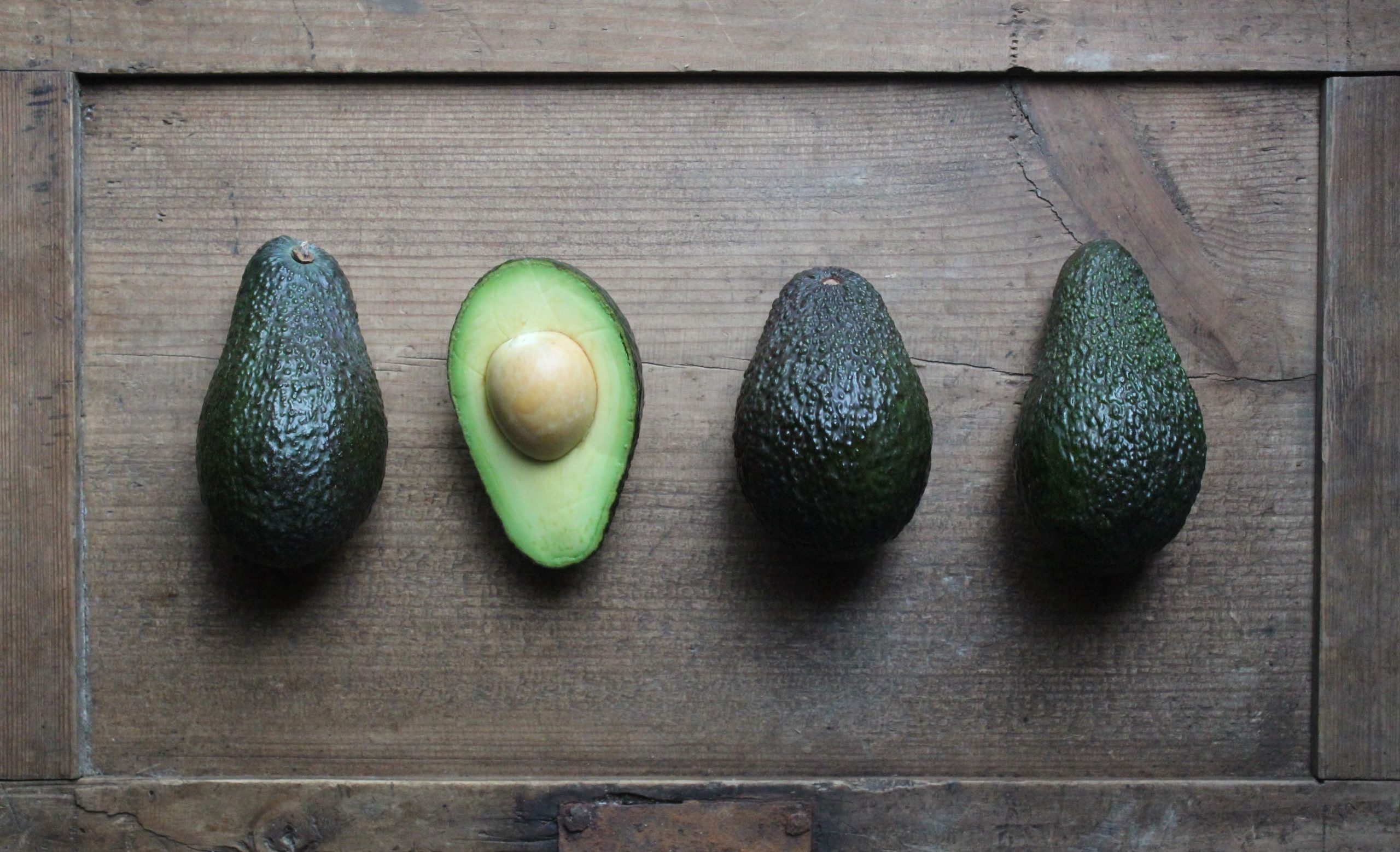 One half, upturned avocado among a trio of unopened avocados as part of an article about niche marketing.