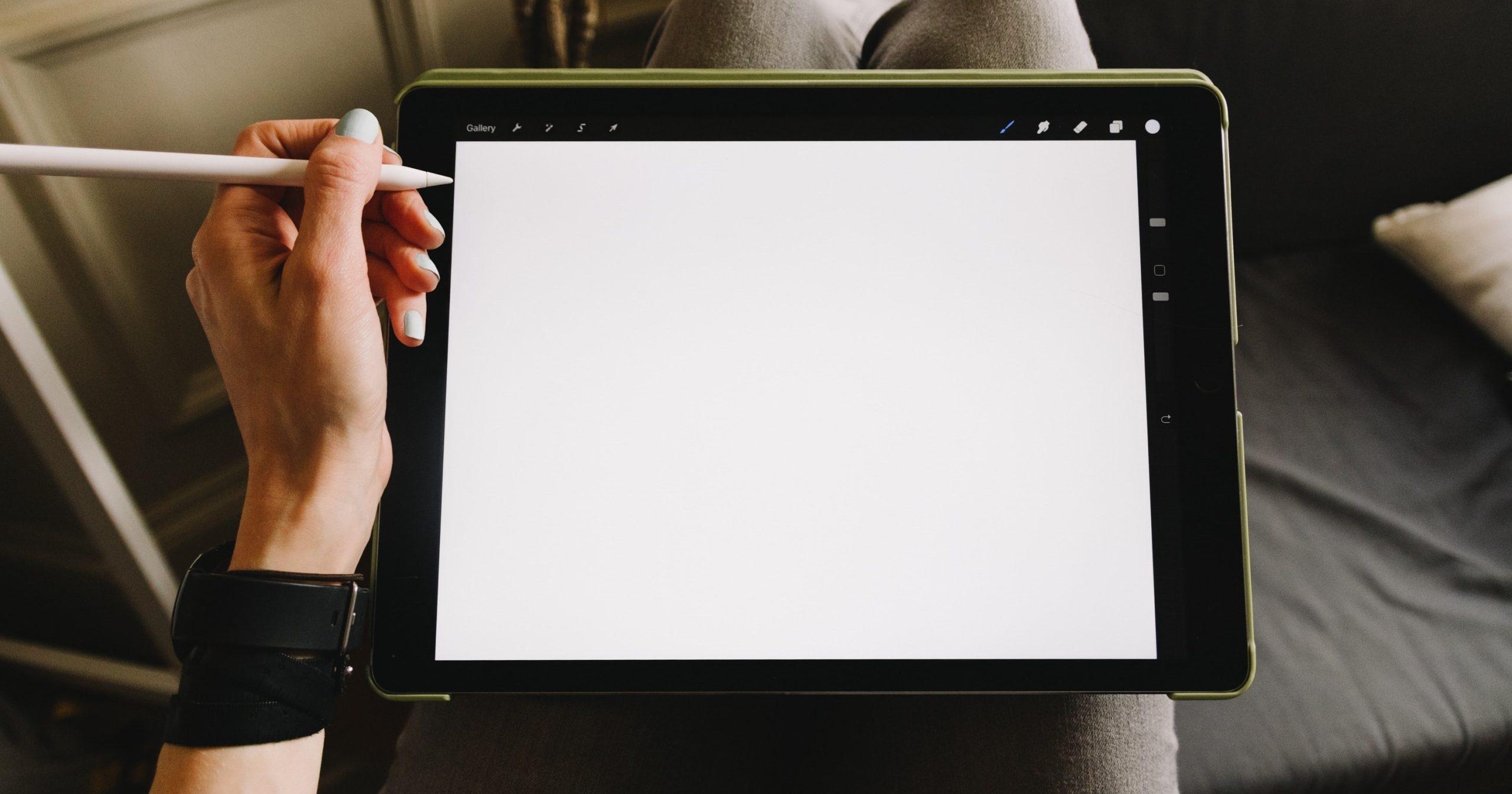 Person holding a tablet device that's displaying a blank, white screen.