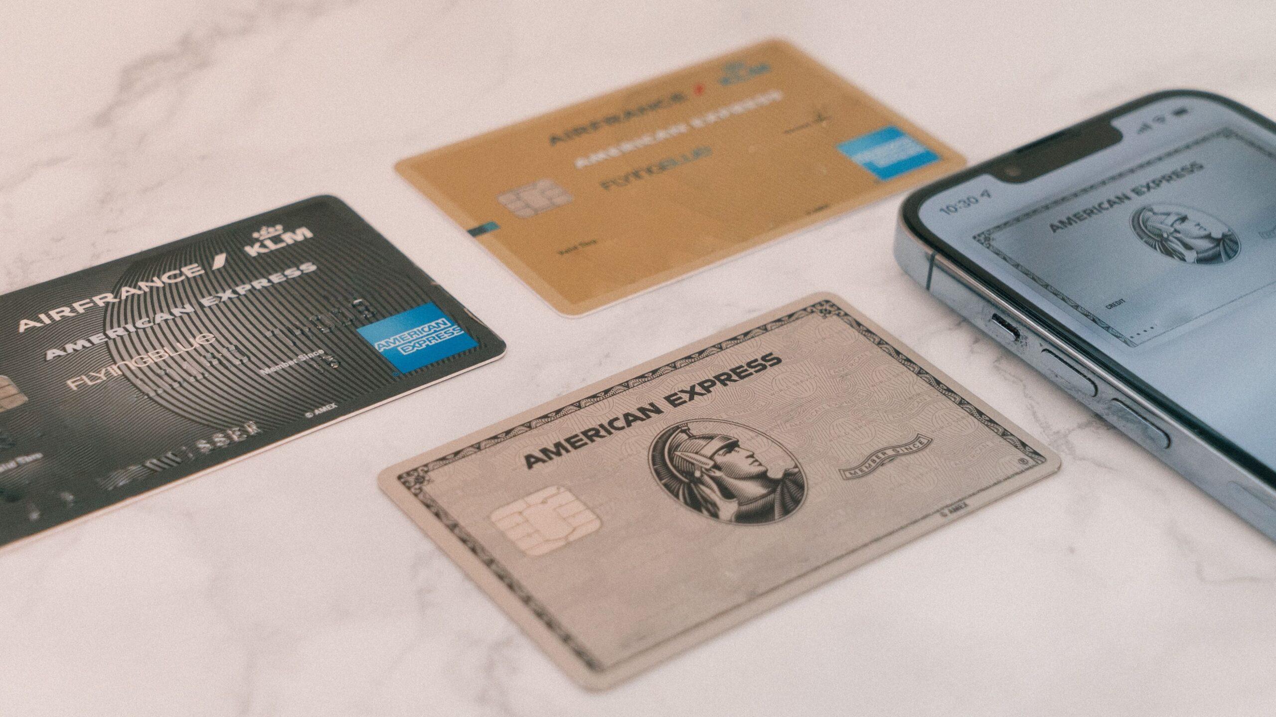 American Express credit cards appearing on a flat surface next to a smartphone.