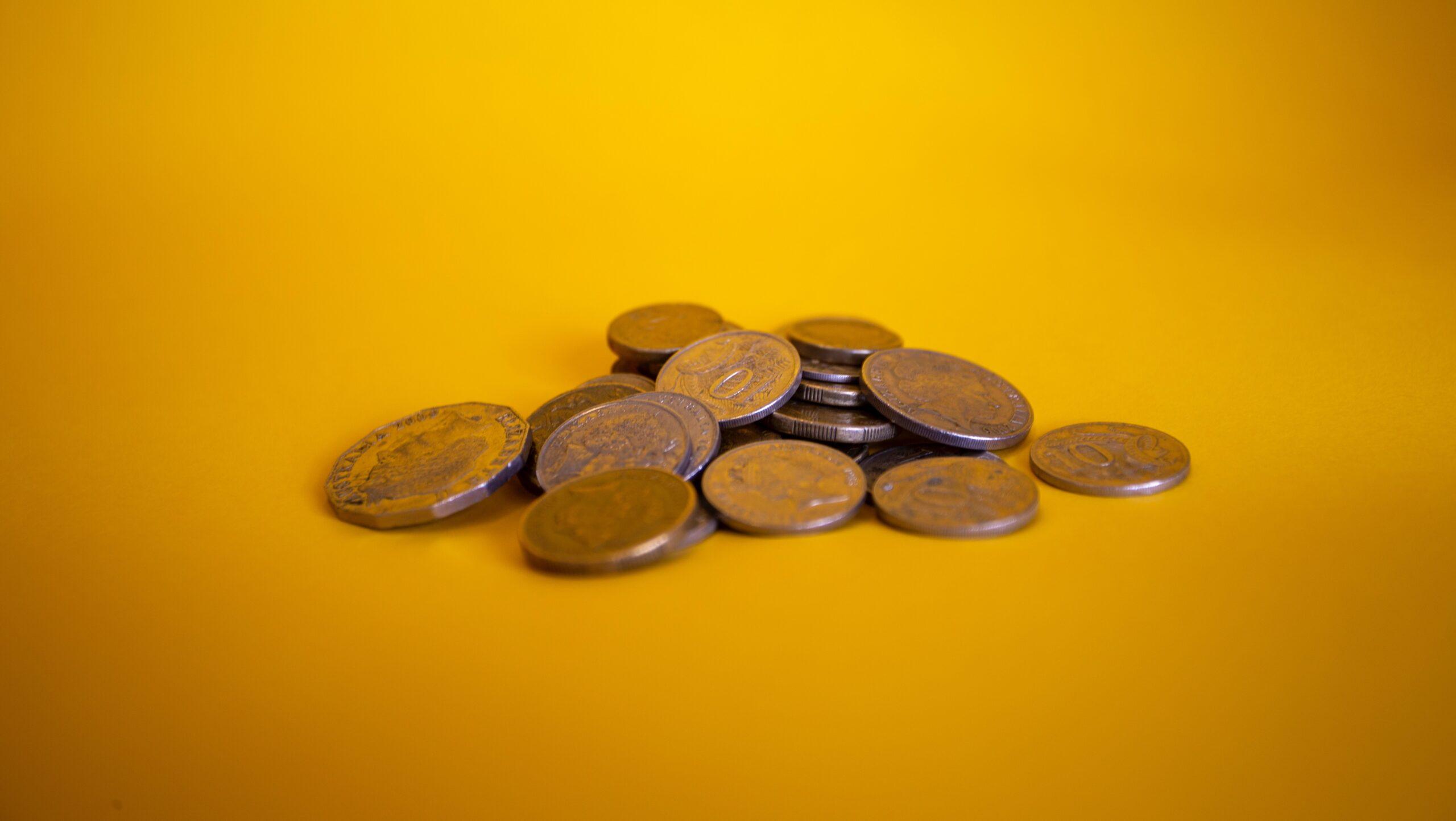 Australian coins in a pile against a yellow background.