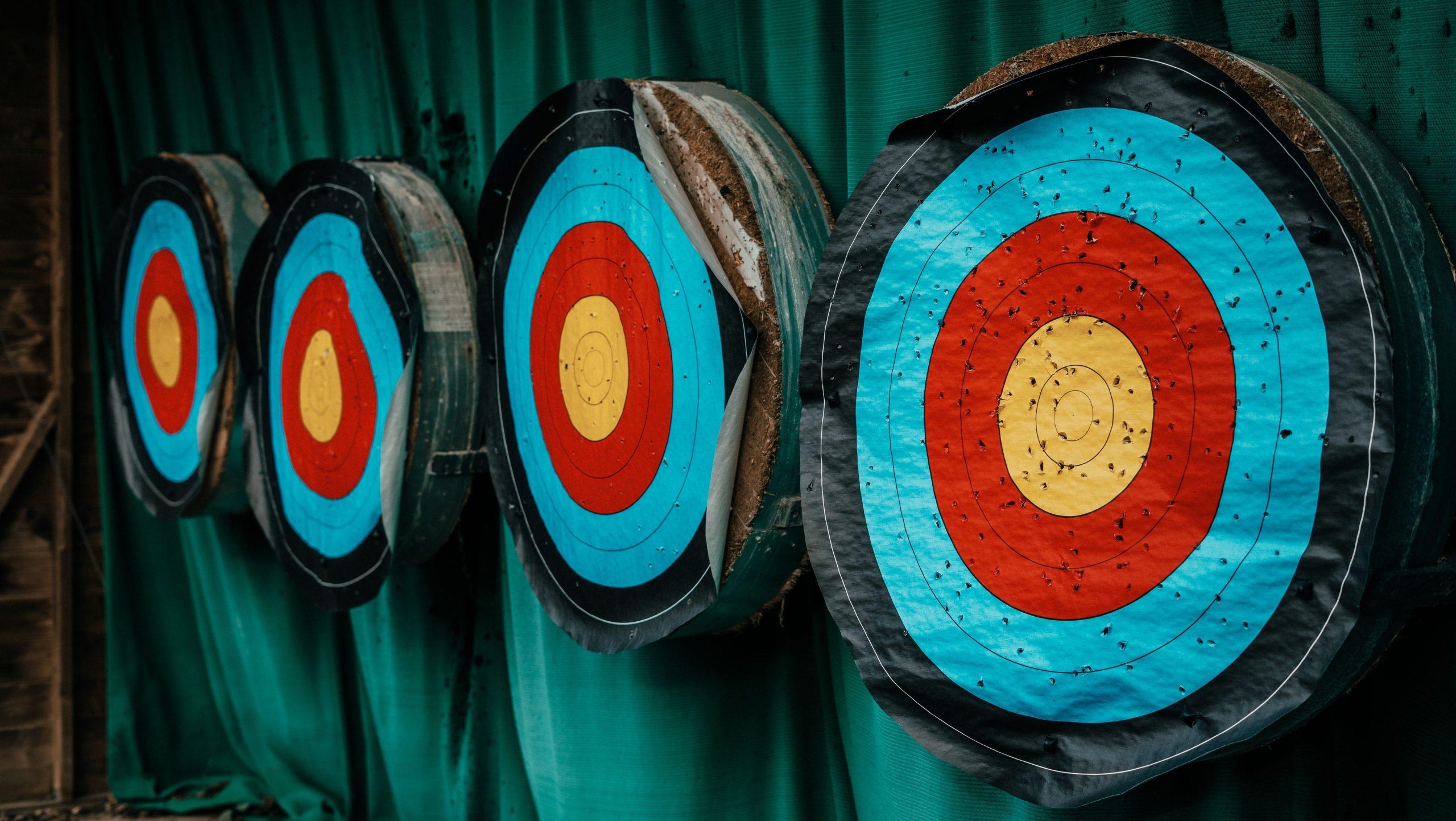 Archery targets lined up against a green curtain.