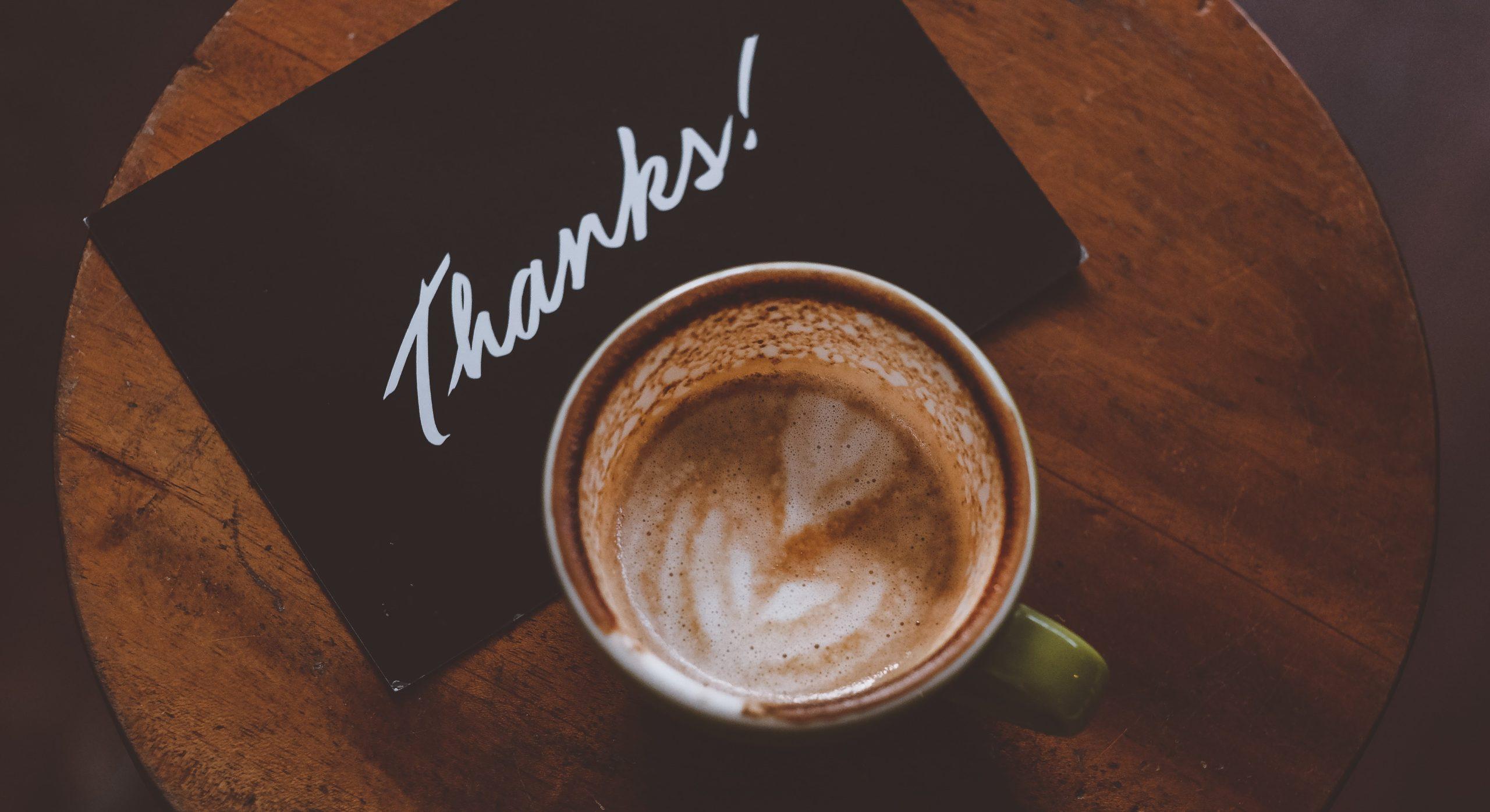 Cup of coffee placed on top of a thank you card. 