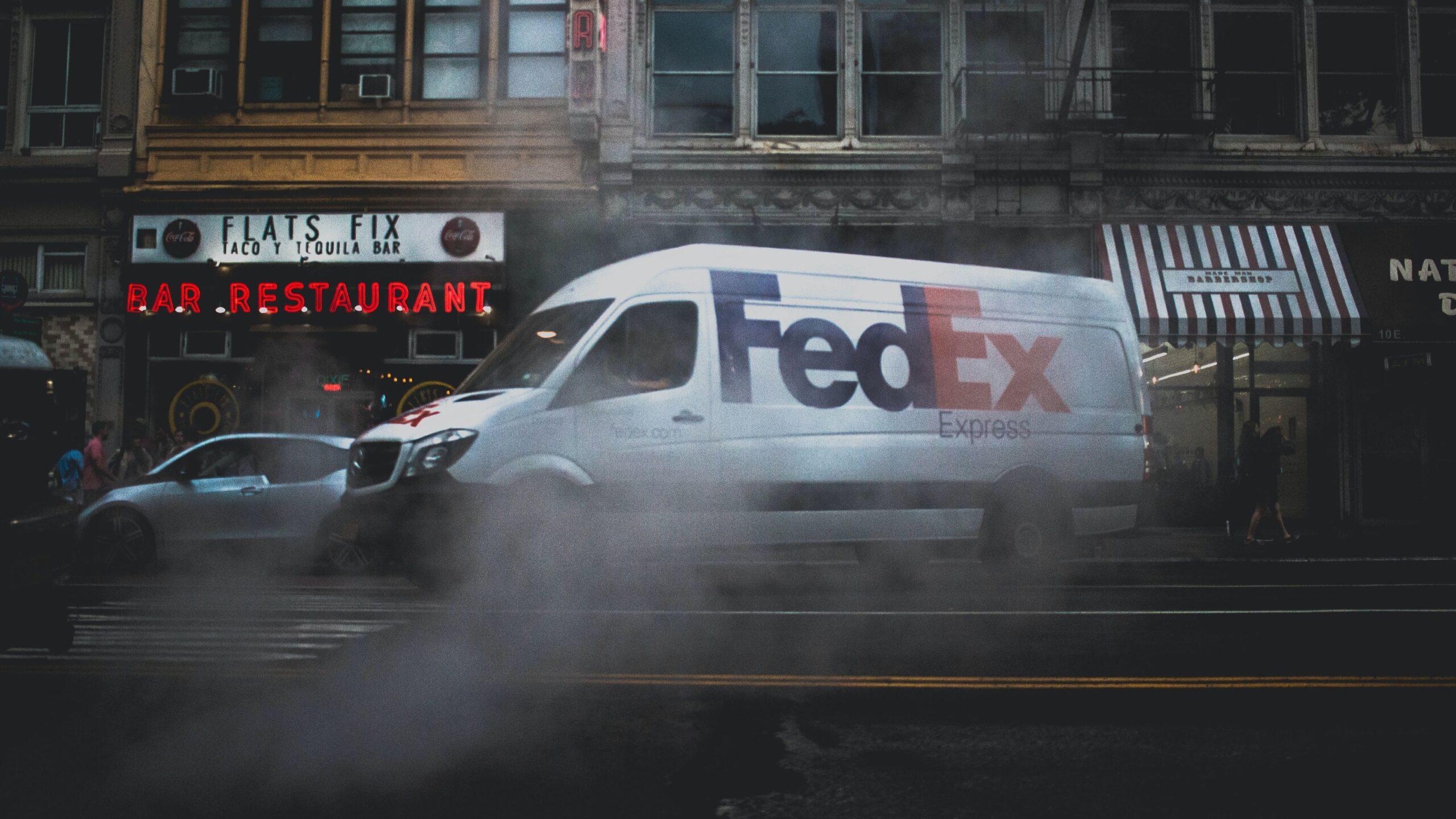 A FedEx van pictured in front of a taco bar and restaurant.