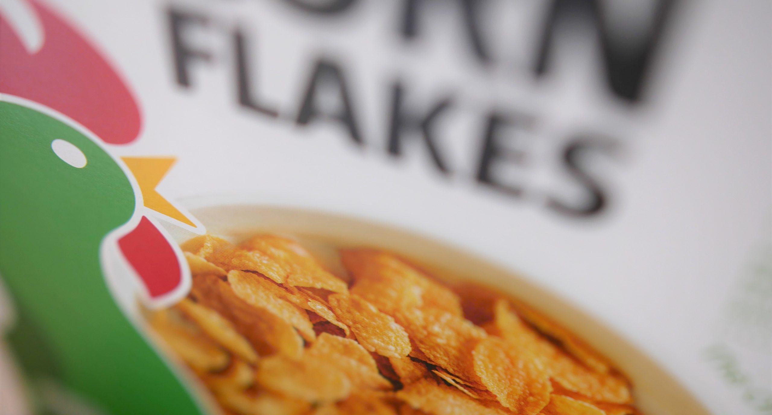 Close up of a bowl of Kellogg's Corn Flakes against a backdrop of the cereal packet.