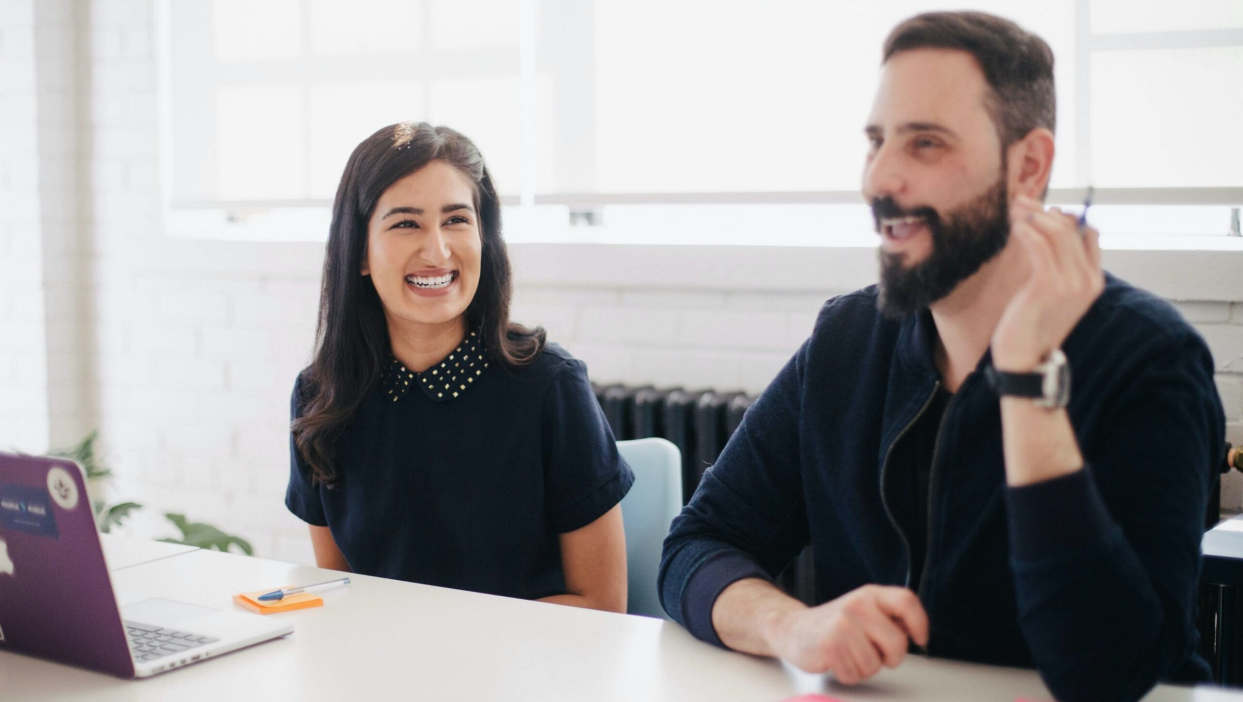 A man and woman smiling in an office-like setting.