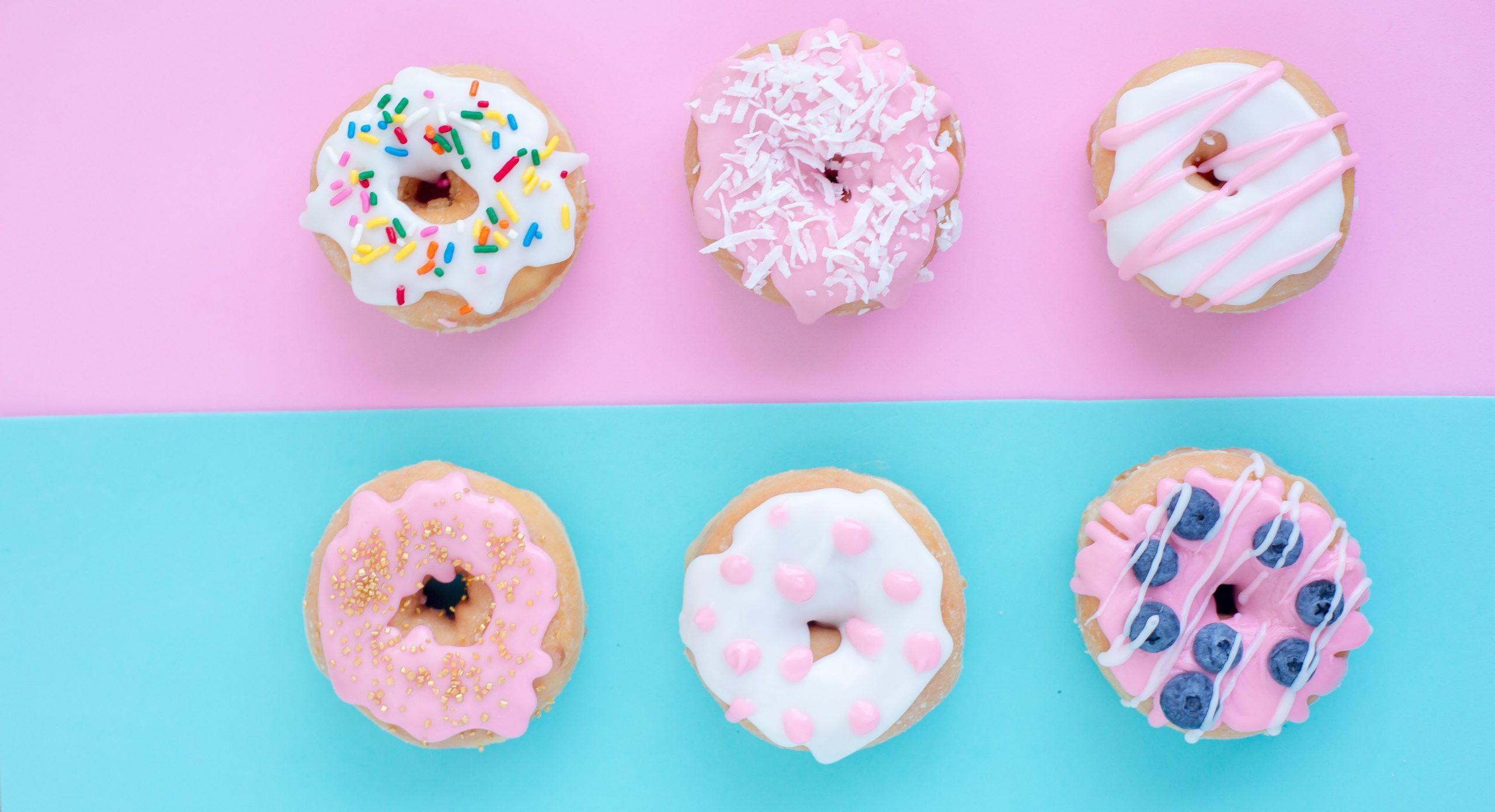 Variable iced donuts placed against a pink and blue background.