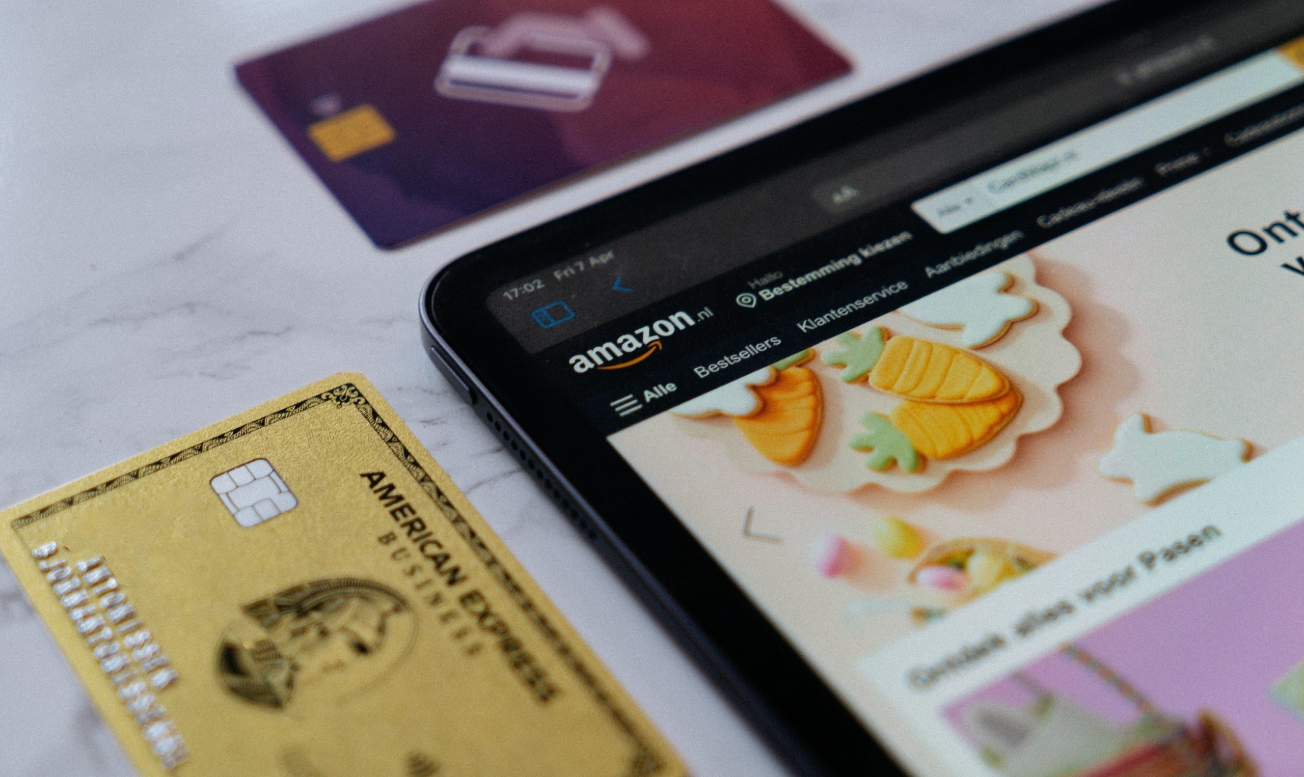 Credit cards on a table next to a tablet device.