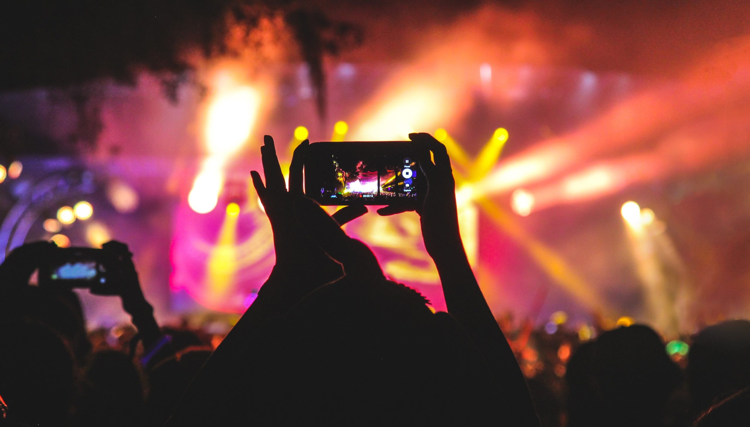 Silhouette of someone holding a smartphone while watching a live event.