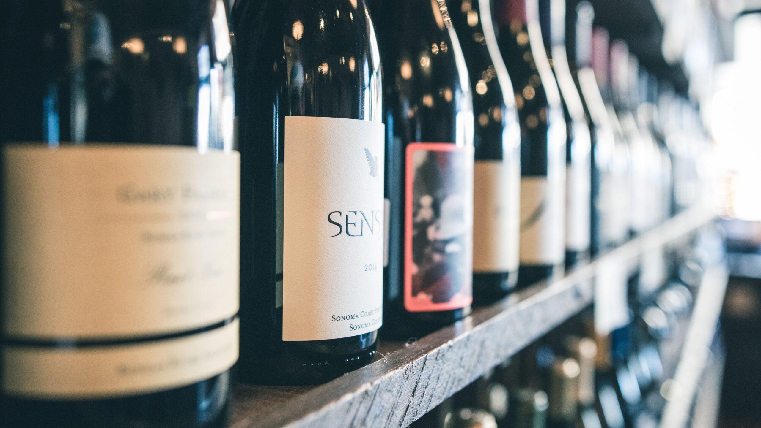 Wine bottles lined up on a shelf.