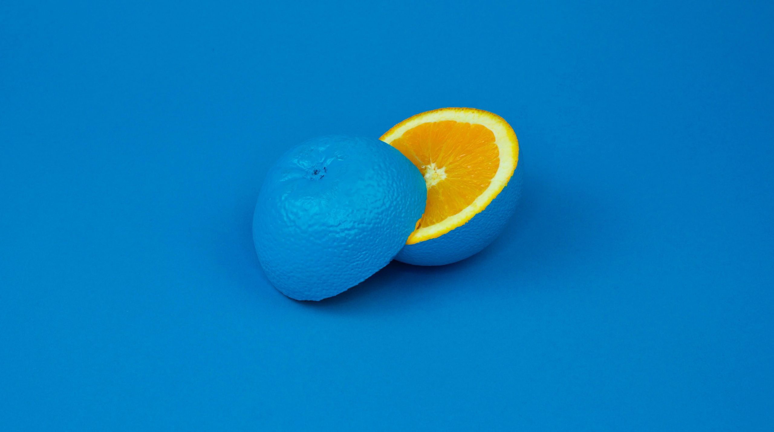Sliced orange with blue coating and a blue background.