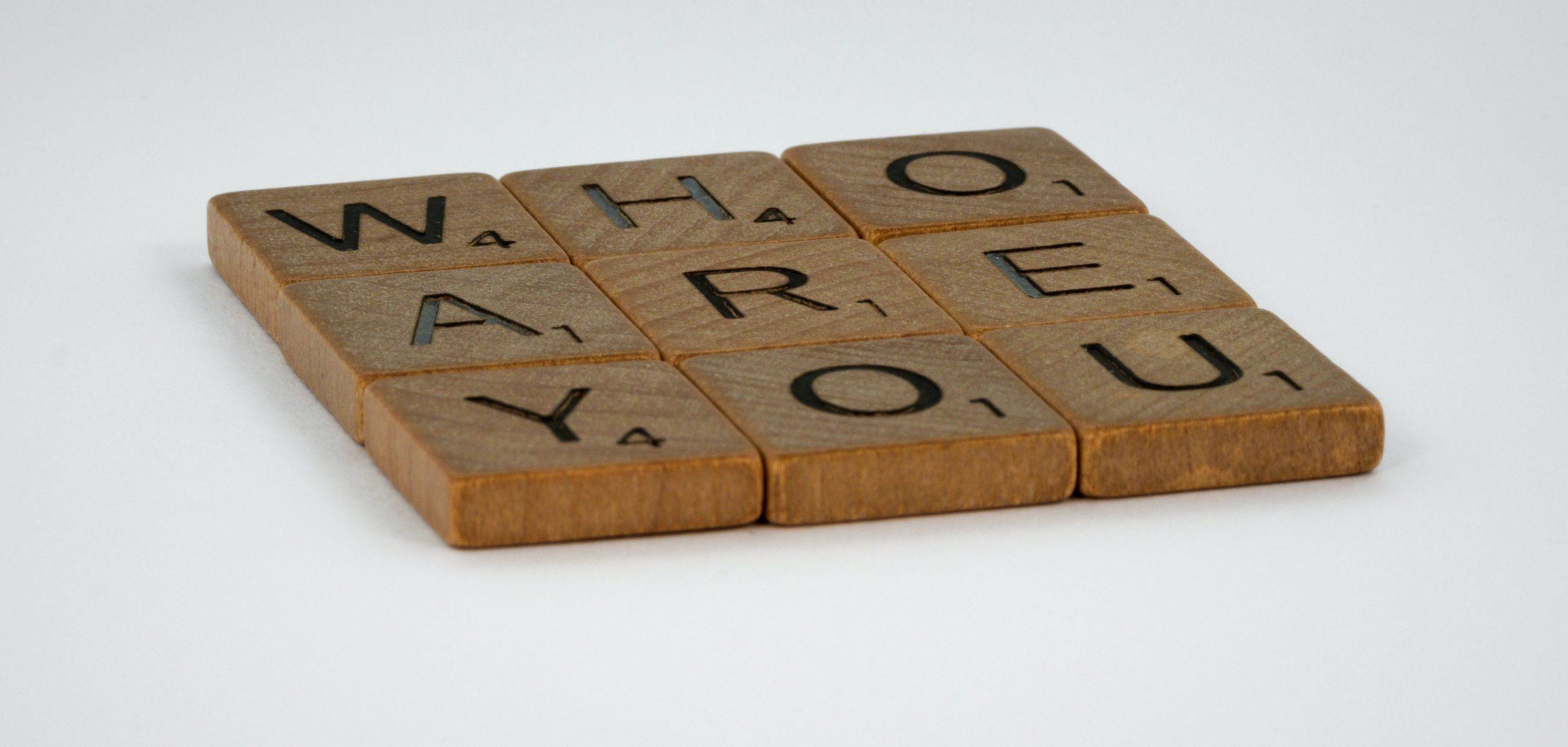 Scrabble letters creating the words 'who are you'.