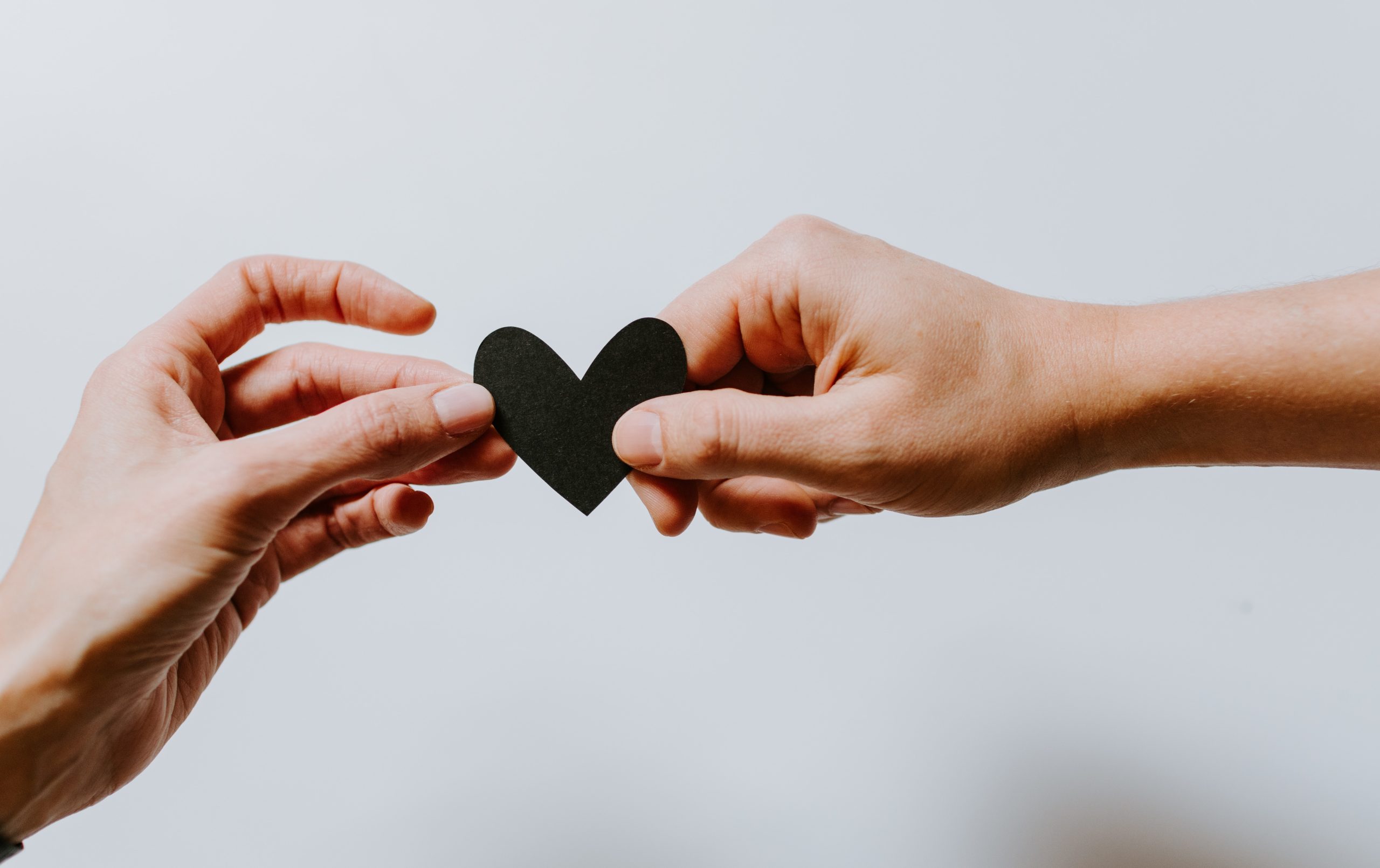 Two hands holding a heart-shaped piece of material.