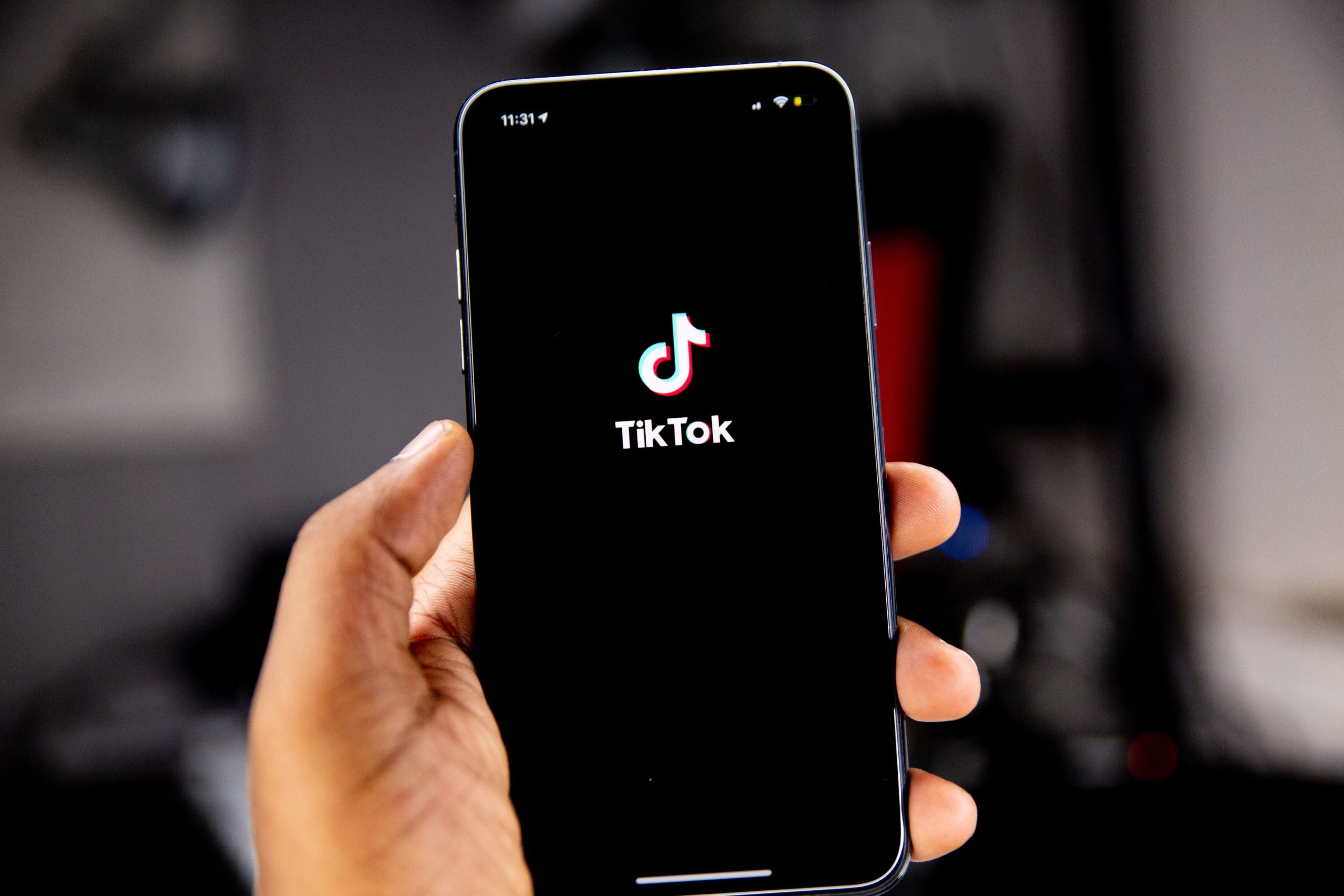 Someone holding a mobile phone displaying the TikTok home screen.