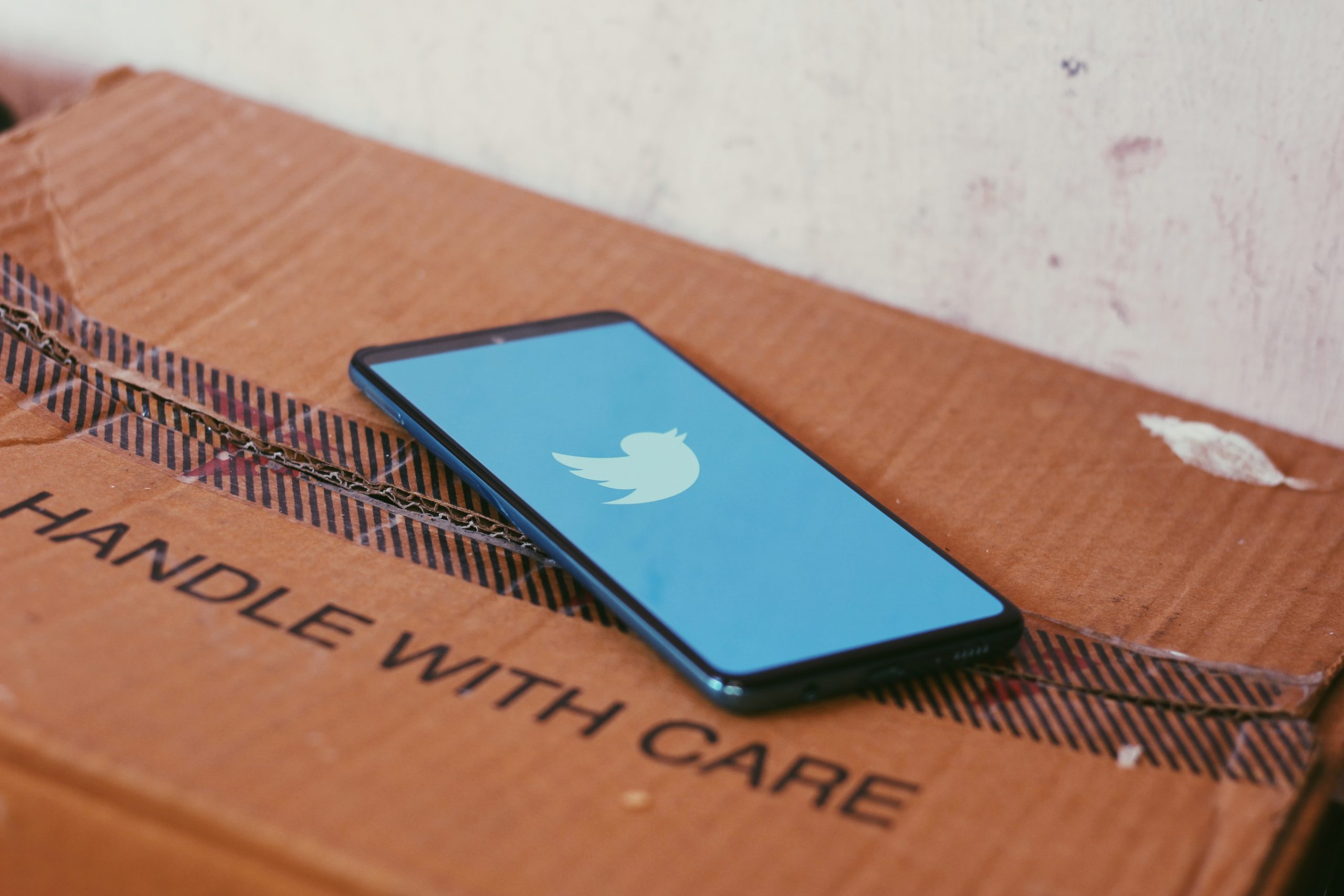 Mobile phone on box displaying the Twitter logo.