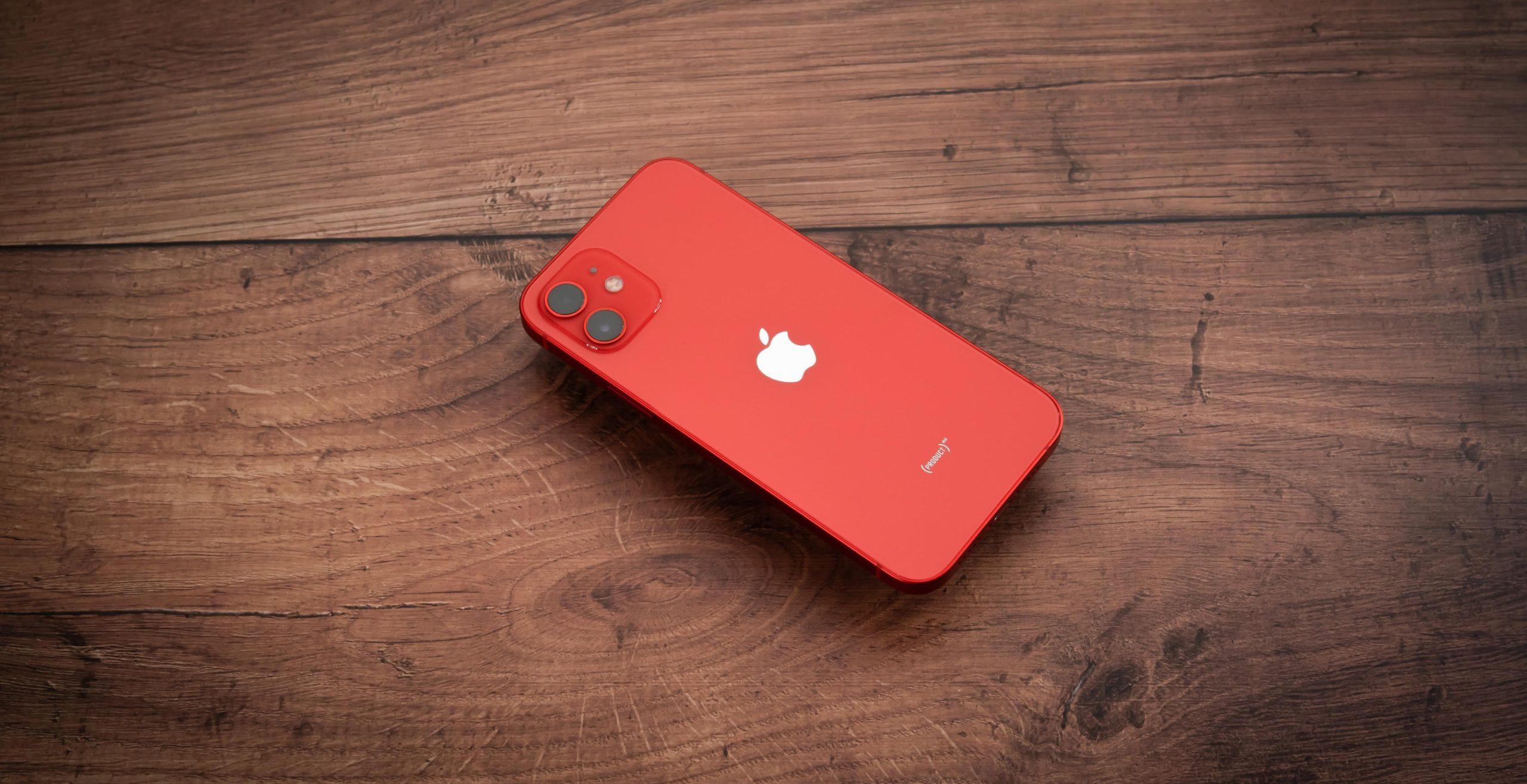 Red Apple iPhone placed on a wooden surface.