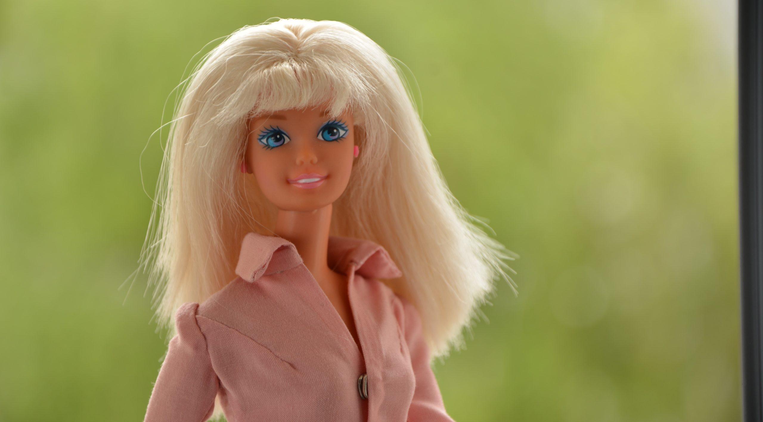 A Barbie doll against a softened, green background.