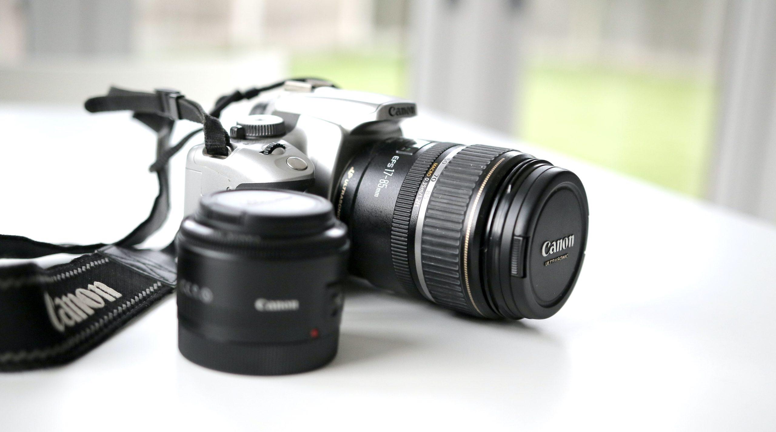 A Canon DSLR camera placed on a white table.