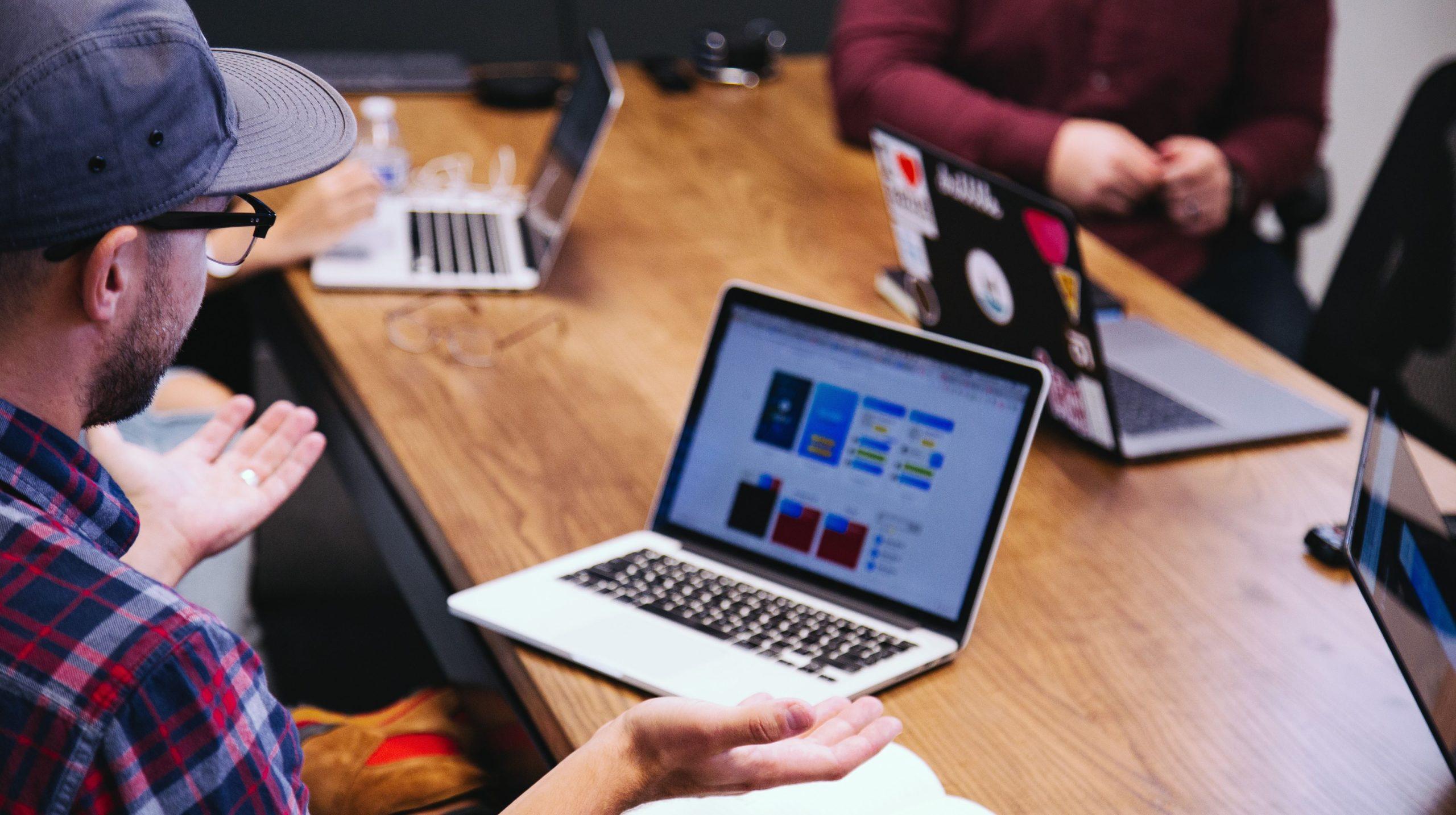 People with laptops in front of them grouped in a meeting room.