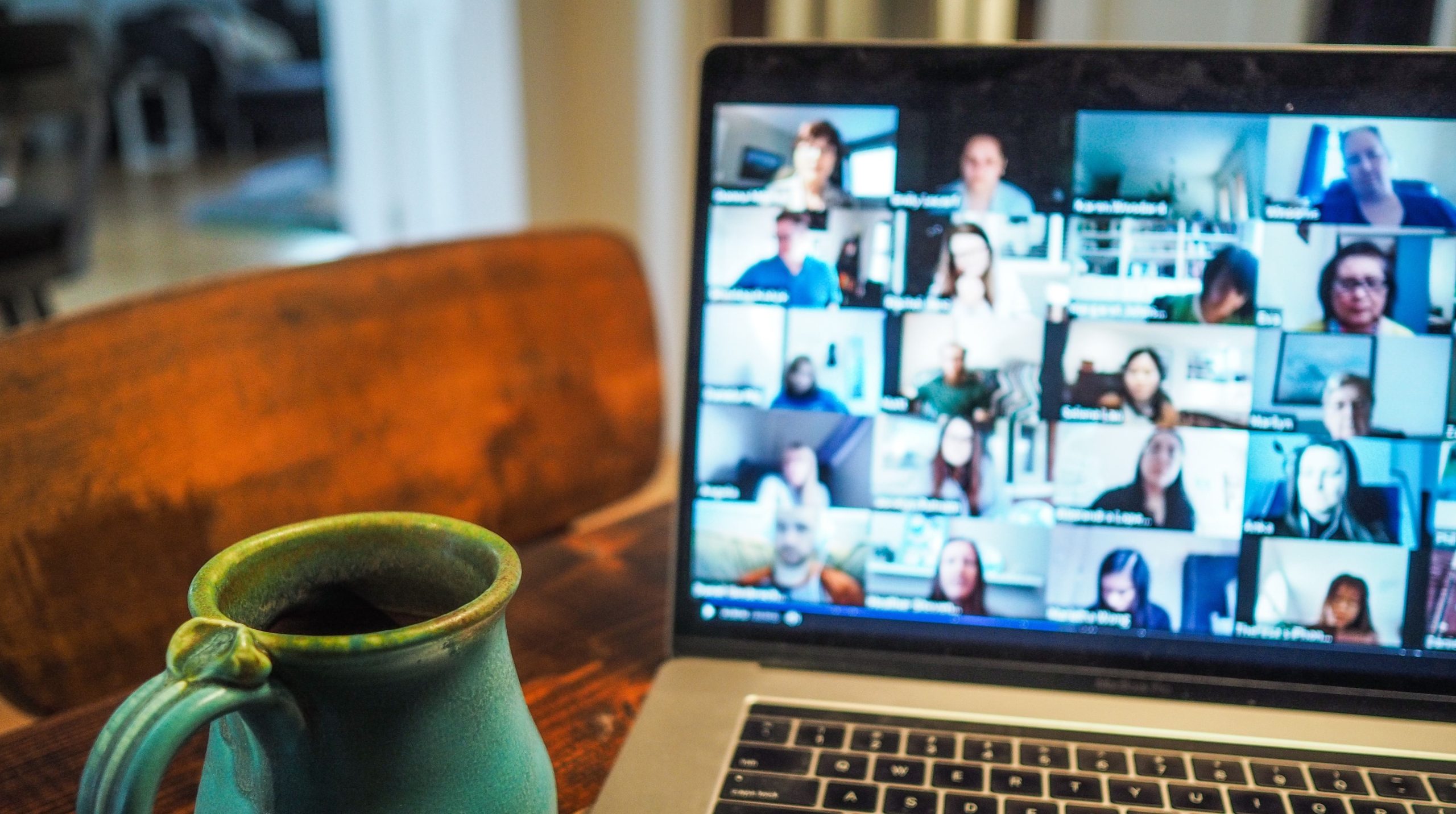 Laptop showing faces of people as part of a video call.