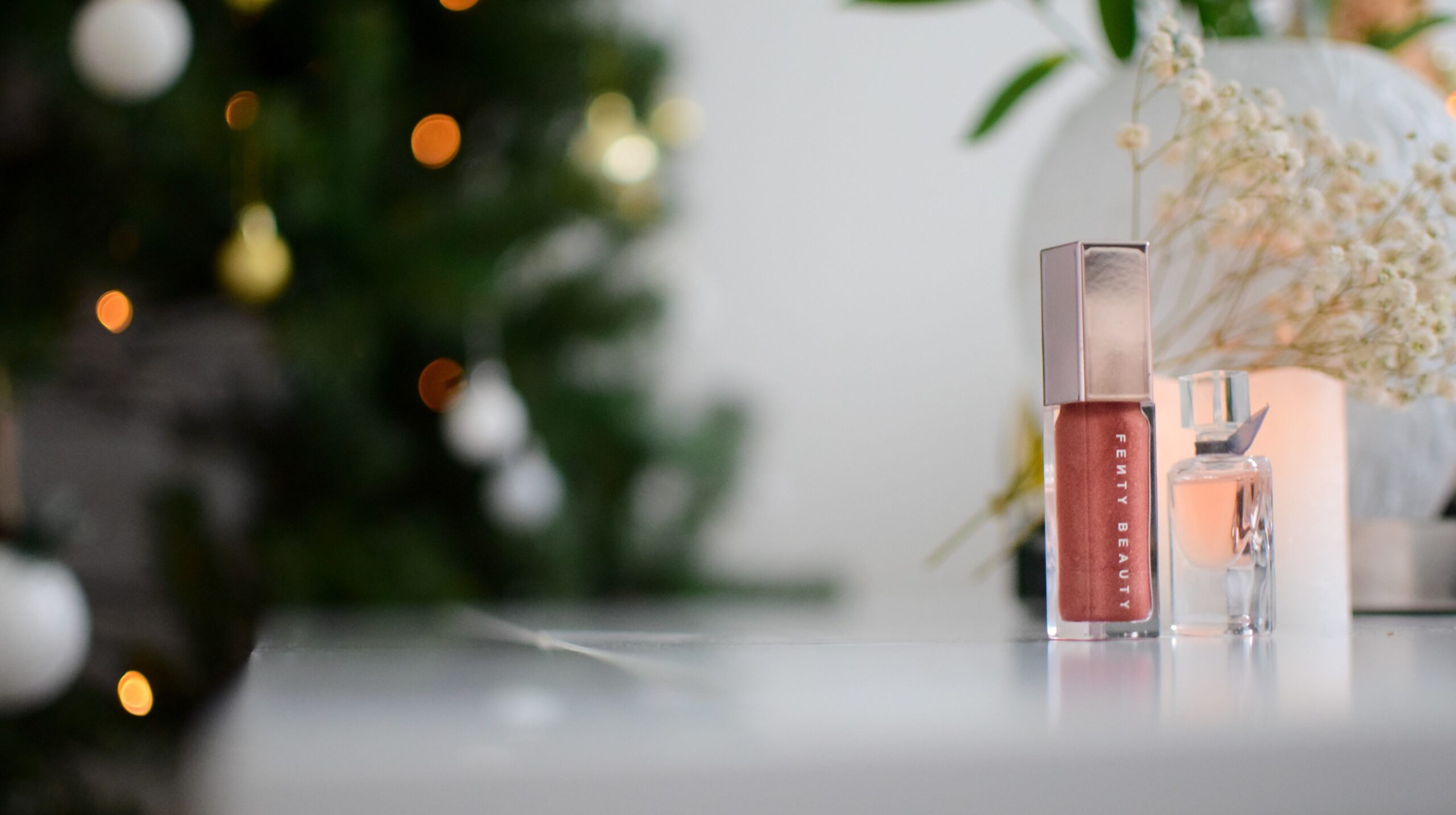 Fenty Beauty products in front of a blurred Christmas tree.