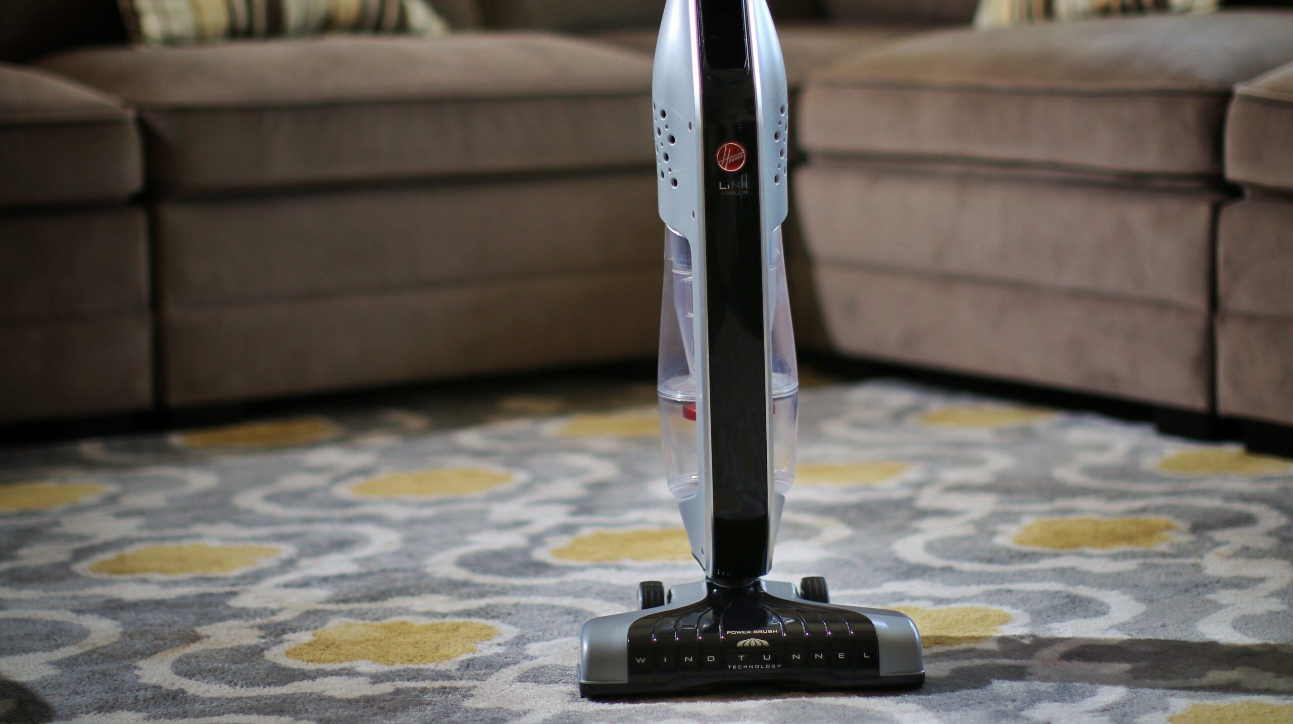 A Hoover vacuum cleaner upright on a carpeted floor.