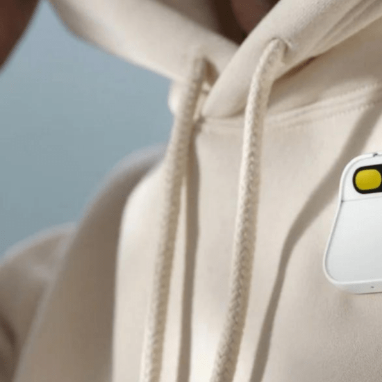 Close up of a person in a hooded jumper wearing a Humane AI Pin.