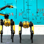 Two Boston Dynamics’ ‘Spot’ robot dogs stand in front of a canvas painting.