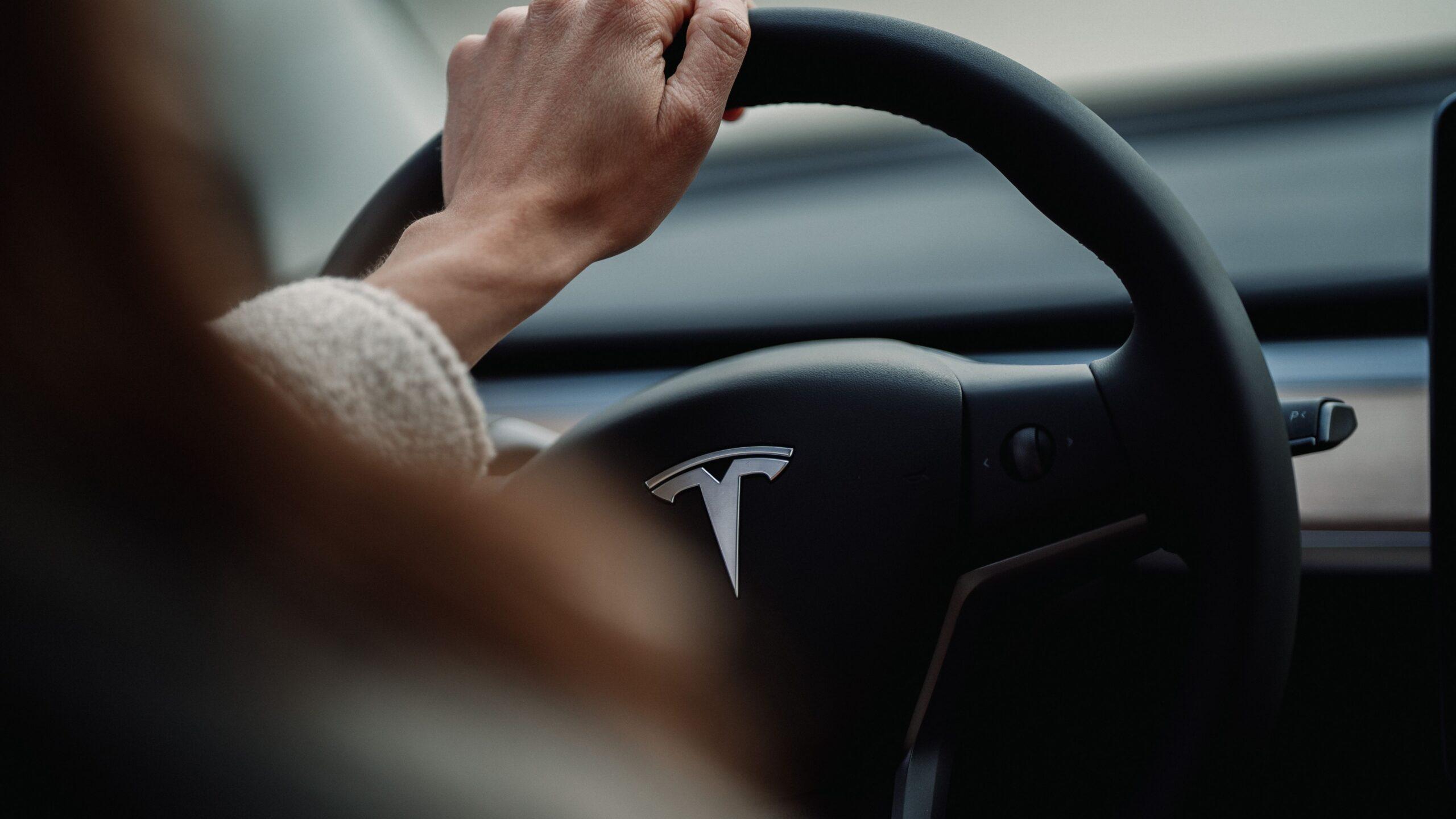 Close up of a person driving a Tesla car.