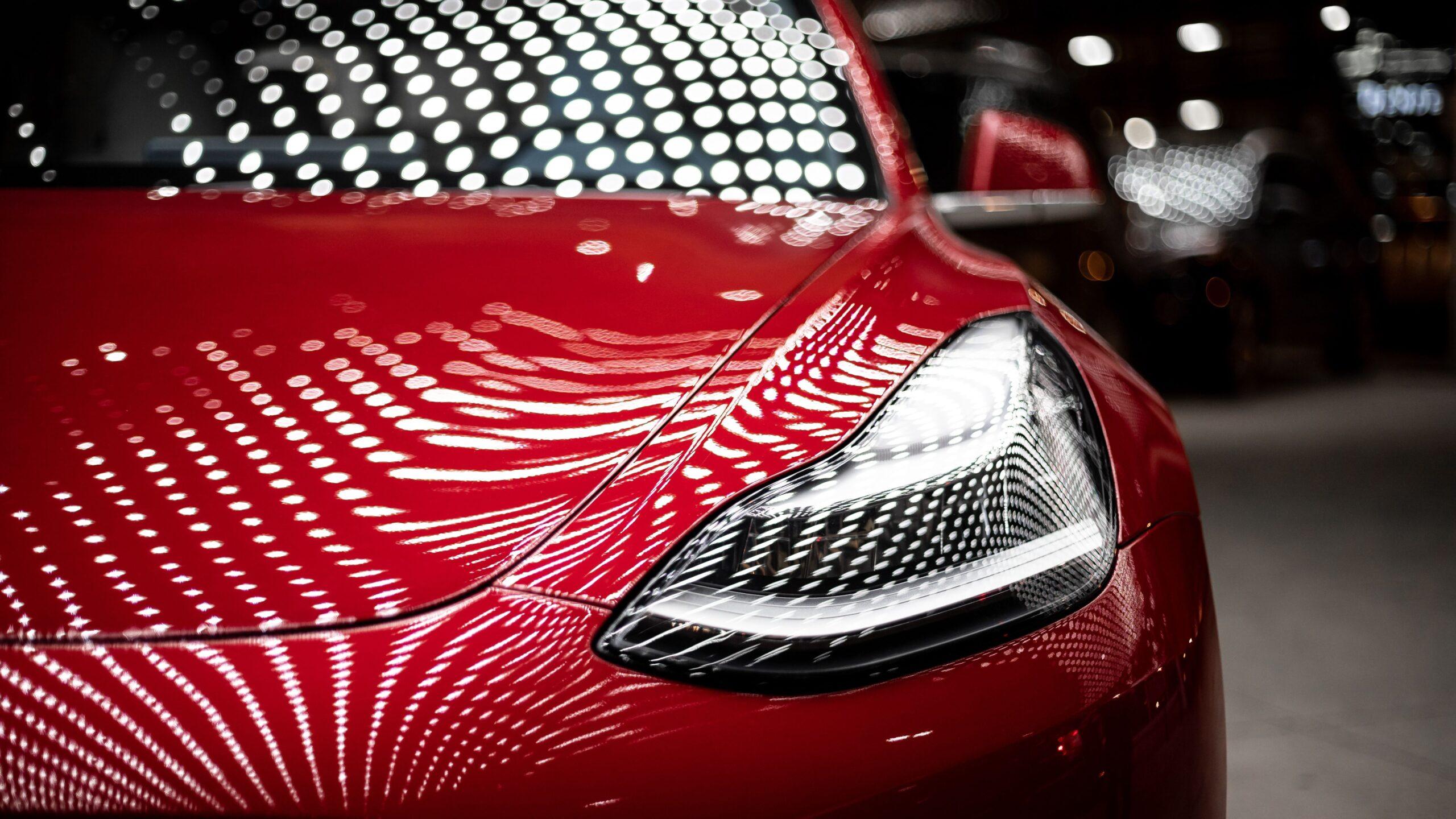 Close up of the front exterior of a red Tesla vehicle.
