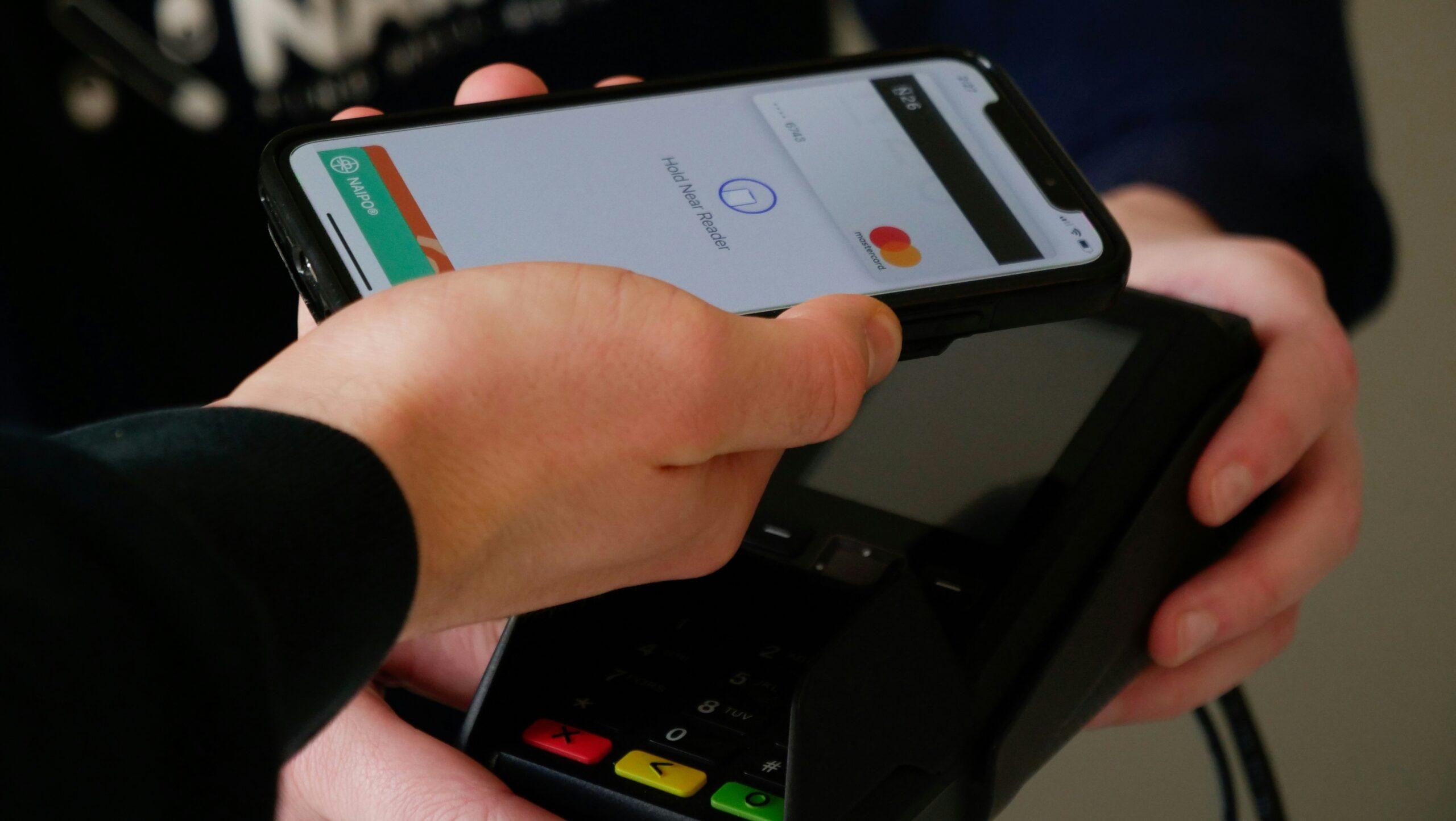 Person holding a smartphone against a card reader.