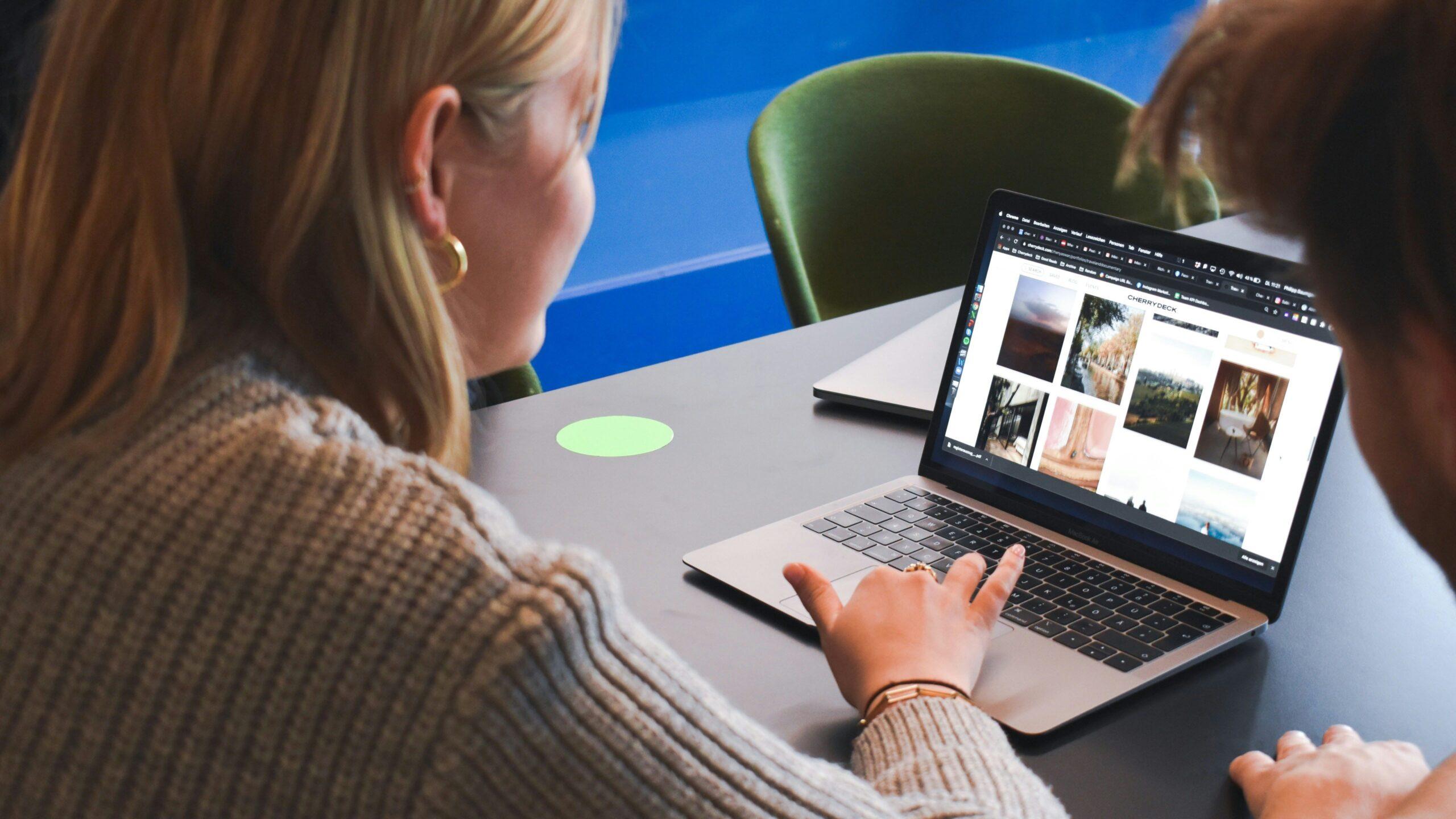 Woman interacting with a laptop displaying various images.