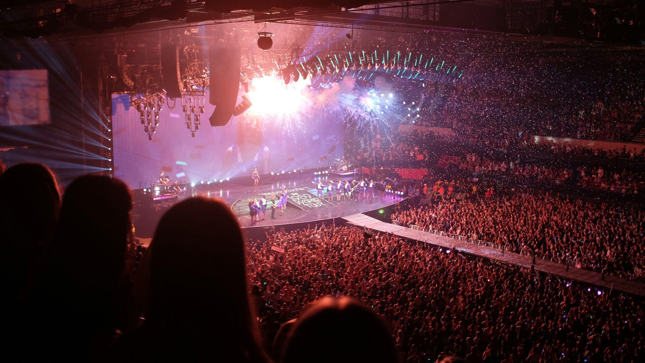 Taylor Swift on stage at a concert that is packed with people.