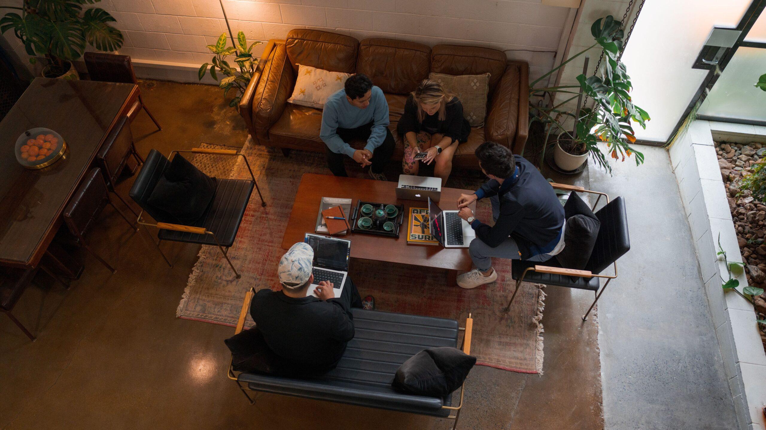 Aerial of professionals sitting on sofas and chairs interacting in an office-like environment.