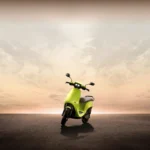 A lime green Ola Electric scooter upright against a backdrop of the sky and setting sun as part of an article about autonomous scooters.