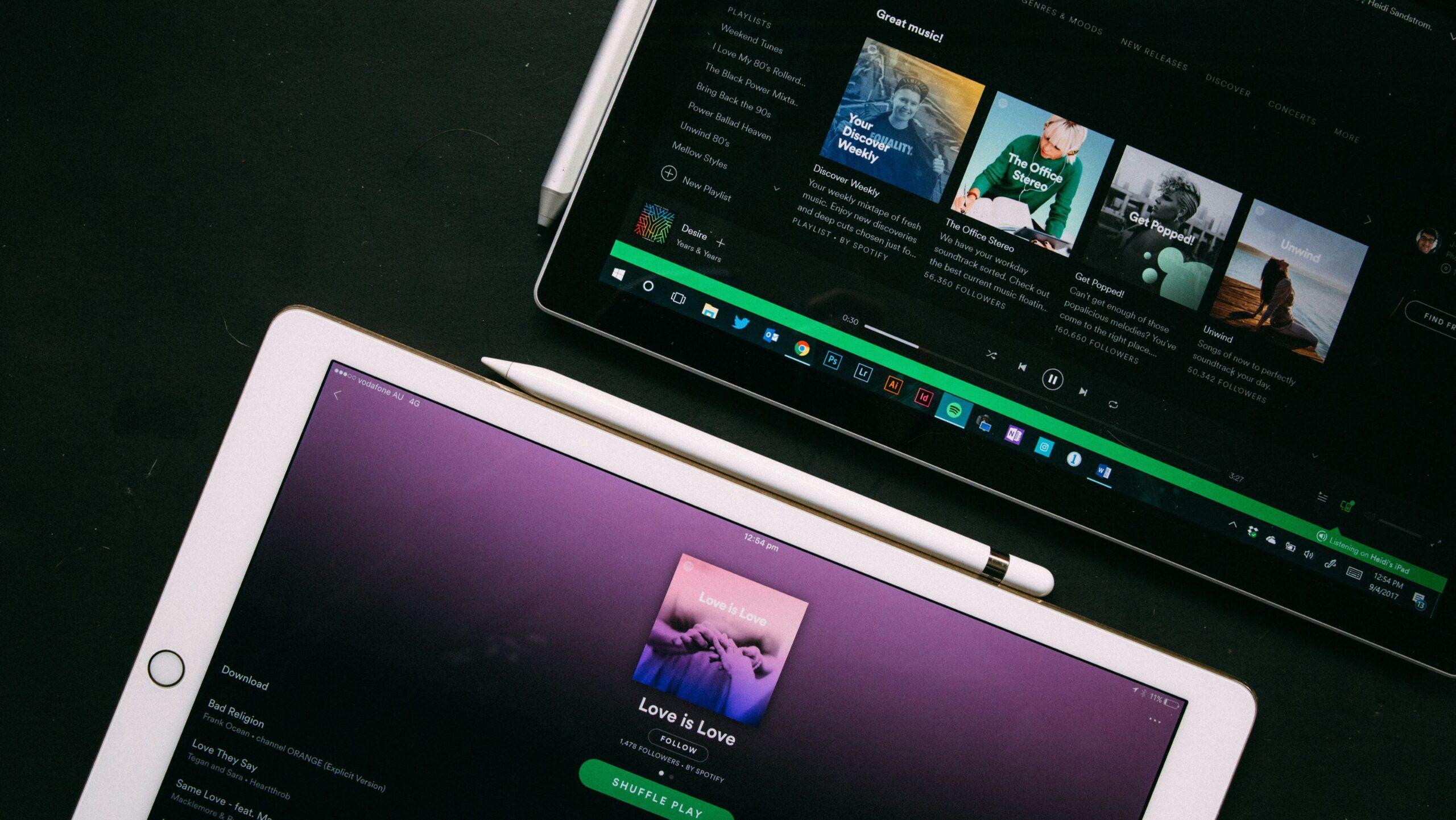 A laptop and tablet both displaying Spotify website pages.
